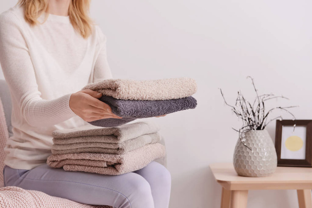 Nainen taitto puhtaita pehmeitä pyyhkeitä sohvalla kotona
 - Valokuva, kuva
