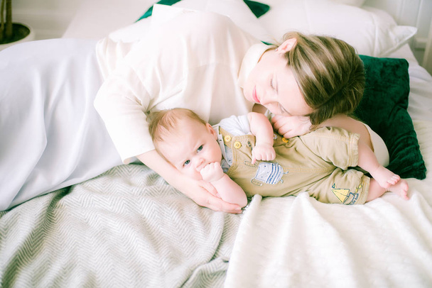 Portrait of beautiful mom playing with her 4 months old baby in bedroom - Image - 写真・画像