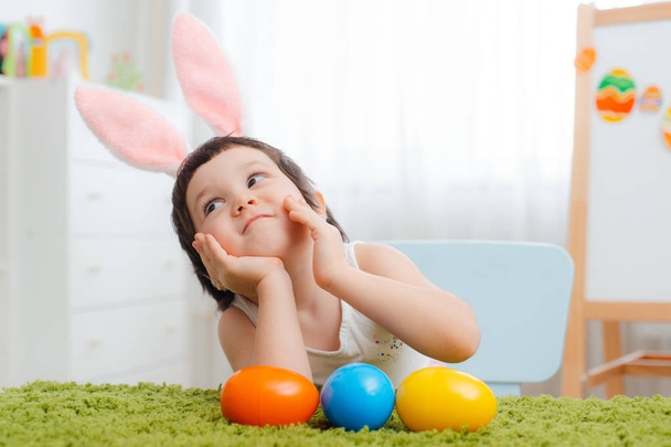 Niña en orejas de conejo están jugando con huevos de Pascua. Niños celebrando Pascua
. - Foto, Imagen