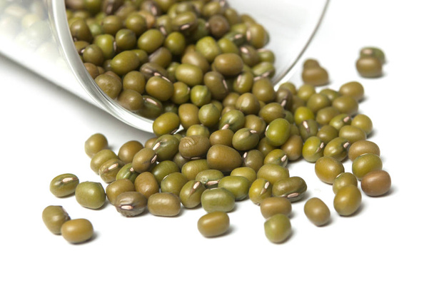 Closeup of mungo beans falling from glass container on white bac - Фото, зображення