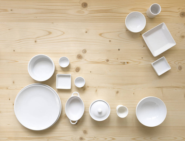 collection of modern white crockery on light wooden background - Photo, image