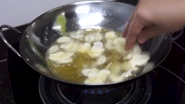 Gezond eten. Frituren van knoflookchips in een pan met hete olijfolie. - Video