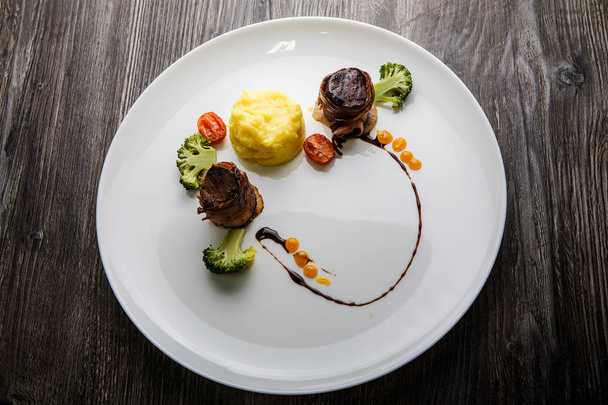 top view two tasty meat pieces roasted in bacon with puree and broccoli - 写真・画像