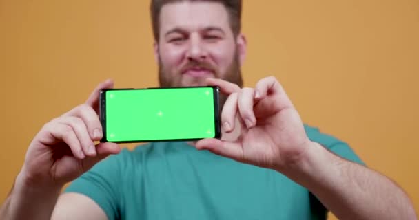 Man proudly shows his phone with green screen on - Video