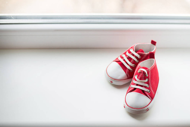 Симпатичные красные кроссовки небольшого размера на белом фоне с копировальным пространством
 - Фото, изображение