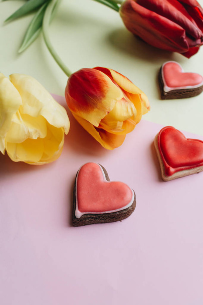 sušenky ve tvaru srdce s červenou glazurou a jarní tulipány  - Fotografie, Obrázek