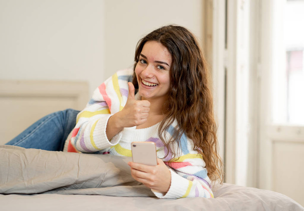 Happy attractive young teenager woman on smart phone checking followers and chatting online using mobile application at home in communications, internet, social media and new technology concept. - Photo, Image