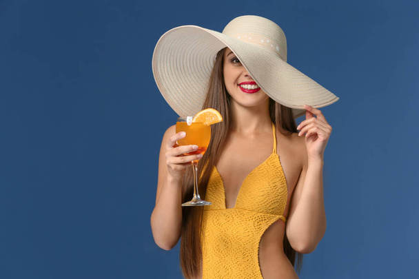 Beautiful woman in swimming suit and with tasty summer cocktail on color background - Photo, Image