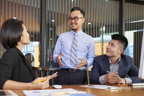 Empresário asiático positivo conversando com investidores em reunião no escritório
 - Foto, Imagem