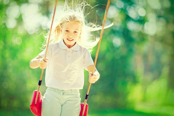 Little girl swinging on a swing outdoors in the forest - Fotografie, Obrázek