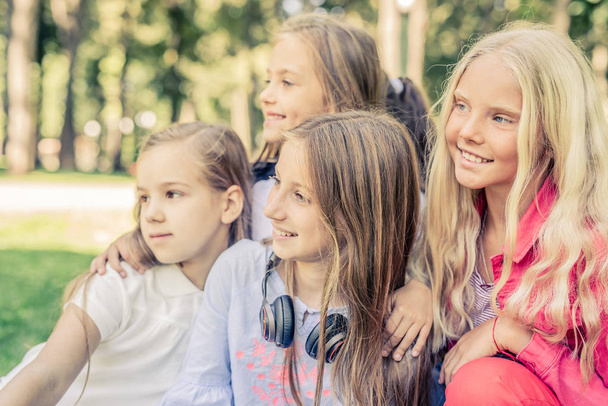 Красивые улыбающиеся маленькие девочки, стоящие вместе в парке
 - Фото, изображение