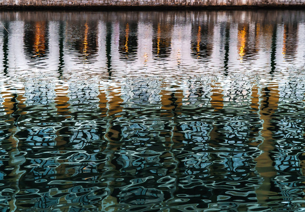 Αντανάκλαση στο νερό του κόλπου που λαμπυρίζει σε πράσινο και πορτοκαλί χρώματα - Φωτογραφία, εικόνα