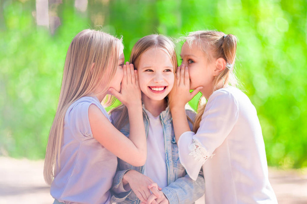 Three cheerful young girls are whispering for a walk in the park. - Foto, afbeelding