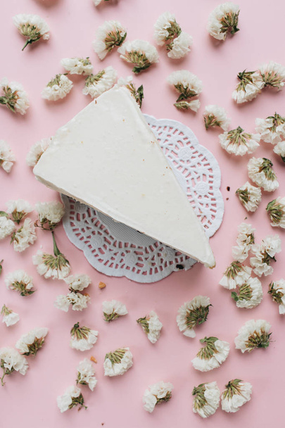 шматок смачного свіжого сирного торта і пелюсток квітів
 - Фото, зображення