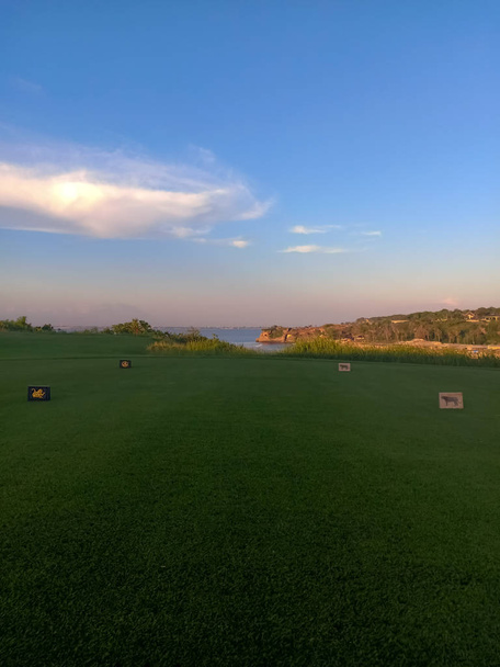 Beautiful green golf course in exotic island Bali at sunset. Green field, blue sky and white clouds. Indonesia 03/05/2019 - Zdjęcie, obraz