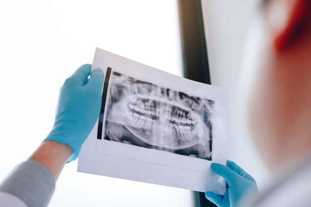 Aziatische mannelijke tandartsen zijn het analyseren van x-ray beelden van patiënten op th - Foto, afbeelding