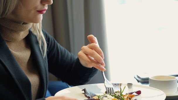 mujer irreconocible comiendo ensalada sentada en la cafetería
 - Foto, imagen