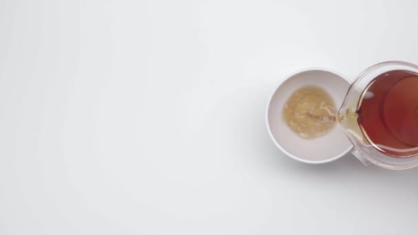 Les mains féminines versent un thé dans une tasse chinoise de bouilloire en verre sur fond blanc. Au ralenti. Cérémonie du thé. Partie 41
. - Séquence, vidéo