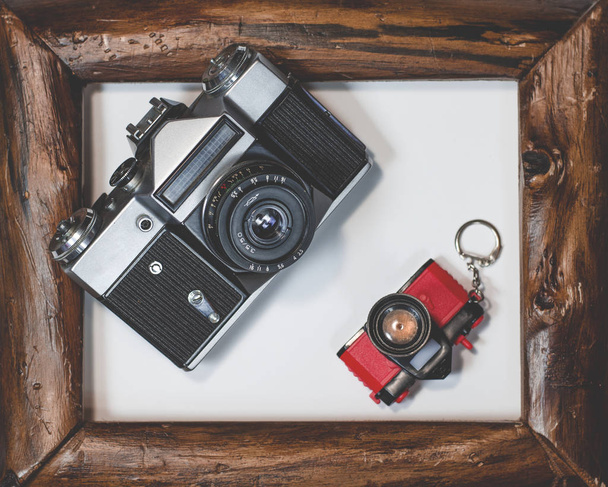 Two old camera lie in wooden frame on a white background - Photo, Image