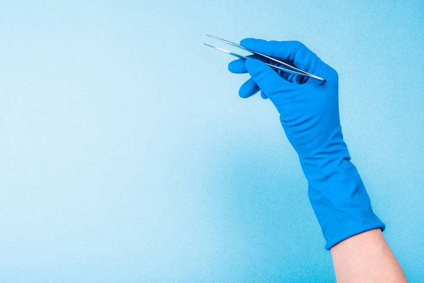 Hand in blue glove holding dental tweezers - Foto, imagen