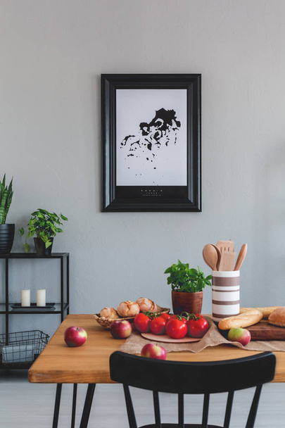 Painting on a wall and dining table with apples, tomatoes and wooden utensils in a dining room interior - Foto, immagini