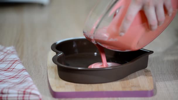 Verter mousse rosa en moldes en forma de corazón. Pastelero haciendo tarta de mousse en la cocina
. - Metraje, vídeo