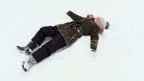 Onnellinen lapsi makaa ja leikkii lumessa
 - Materiaali, video