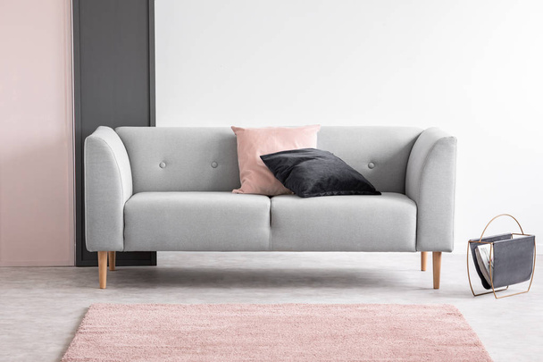 Pastel pink and black design in elegant living room interior with comfortable sofa, real photo with copy space - Fotó, kép