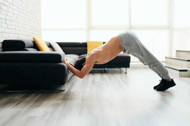 Hombre entrenando pecho y tríceps haciendo cráneos crujientes usando sofá
 - Foto, imagen