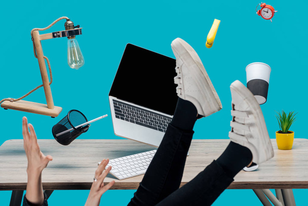 cropped view of woman levitating in air with laptop and stationery at workplace isolated on turquoise - Foto, Imagem