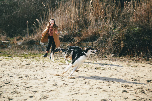 young woman playing with husky dog on riverbank - Φωτογραφία, εικόνα