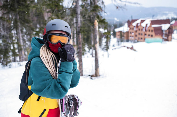 Femme snowboarder se tient avec un snowboard près du centre de loisirs
. - Photo, image