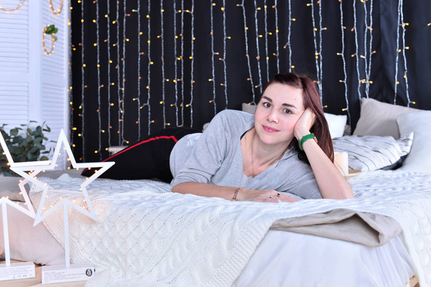 Молодая женщина лежит на кровати
  - Фото, изображение