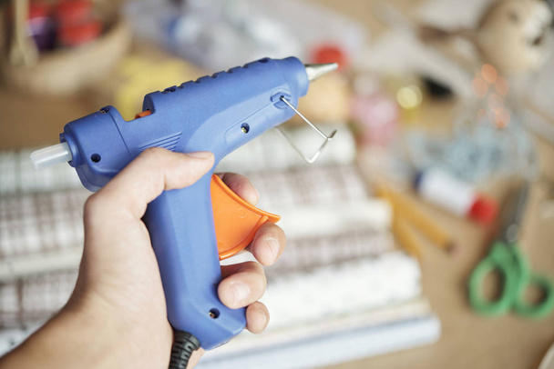 Close-up of hand holding electric hot glue gun and using it for artwork or handicraft - Photo, Image
