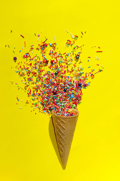 抽象的なカラフルな背景。黄色の背景に色とりどりのキャンディのお菓子。色とりどりの小さなキャンディーのクローズ アップ。アイス クリーム Cone.Minimal アート ・ デザインのお菓子. - 写真・画像