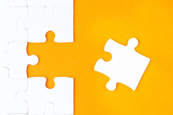 Hand holding piece of white puzzle on orange background. Business and team work concept. - Zdjęcie, obraz