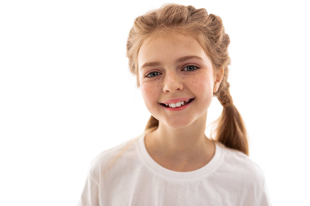 Appealing young girl standing in bright light and smiling - Photo, Image