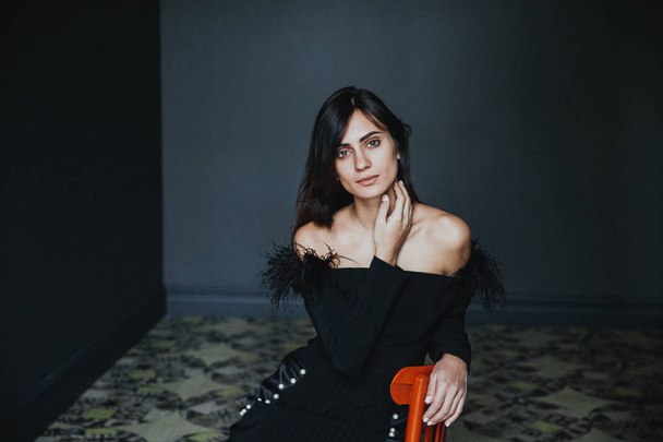 young beautiful woman sitting on chair in dark room - Fotografie, Obrázek