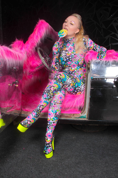 club party blonde girl in acid anime style spandex catsuit with mirror car with pink fur ready for crazy clubbing life - Fotó, kép