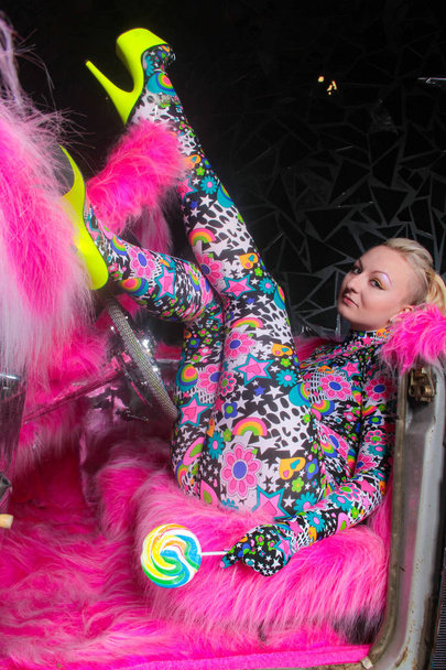 club party blonde girl in acid anime style spandex catsuit with mirror car with pink fur ready for crazy clubbing life - Foto, Bild