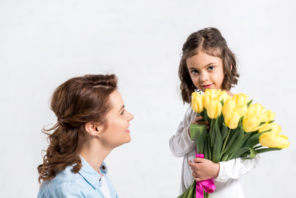 Child giving tulips bouquet to mother isolated on white - Fotó, kép