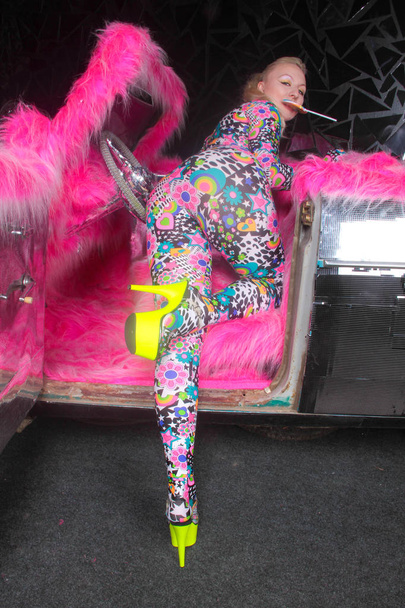 club party blonde girl in acid anime style spandex catsuit with mirror car with pink fur ready for crazy clubbing life - Photo, Image