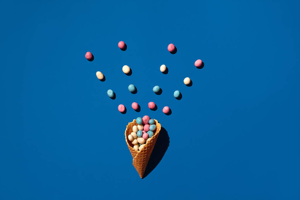 An image of a heap of dragee sweets that is sprinkled from a waffle cone - Photo, Image