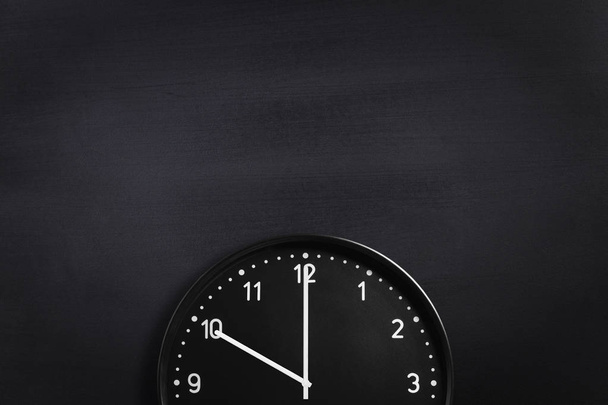 Zegar ścienny czarny na tle czarnej tablicy. Upraw skład - Zdjęcie, obraz