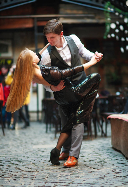 Joyful young couple in love dancing latin on evening street - Foto, immagini