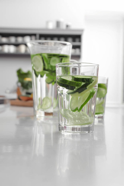 Glass of fresh cucumber water on white table in kitchen - Zdjęcie, obraz