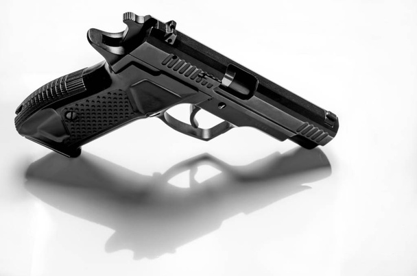 Pistola de metal negro se encuentra sobre un fondo blanco, primer plano
 - Foto, imagen