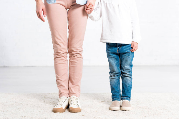 Cropped view of mother and daughter holding hands on white  - Fotoğraf, Görsel