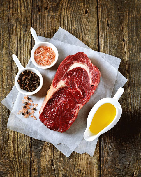 Raw fresh beef steak rib eye on old wooden background. Rustik Style. Top view. - Фото, изображение