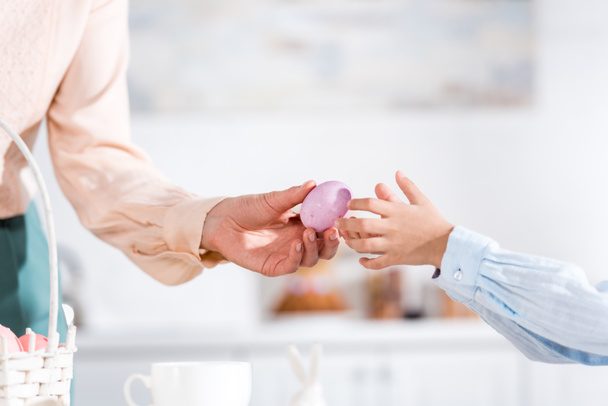 Partial view of woman giving painted easter egg to child  - Photo, Image